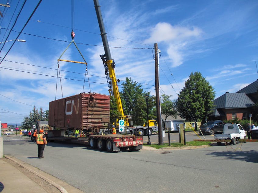 A crane begins to lift a historic boxcar off a flatbed and onto tracks behind the Wolfville Memorial Library. CONTRIBUTED