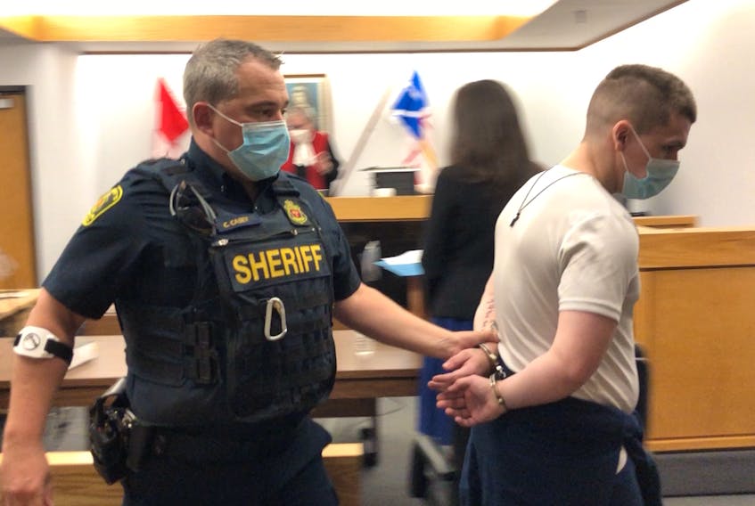 A sheriff's officer escorts Brandon Noftall from a St. John's courtroom Thursday morning, Sept. 9, to allow provincial court Judge Phyllis Harris time to consider his request for a postponement. Noftall — who is also charged with the second-degree murder of his stepfather last December — had been scheduled to go to trial Thursday on charges of intimate-partner violence.
