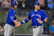  Blue Jays baserunners Jake Lamb, left, and Danny Jansen, right, slap hands after scoring on a single by Marcus Semien during the fourth inning of a game against the New York Yankees at Yankee Stadium in New York City, Wednesday, Sept. 8, 2021.