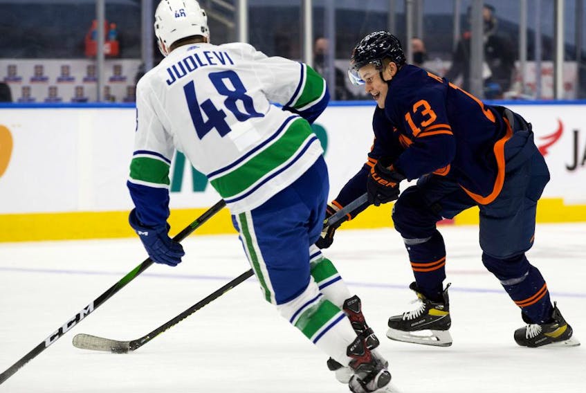 The Edmonton Oilers forward Jesse Puljujarvi (No. 13) battles the Vancouver Canucks defenceman Olli Juolevi (No. 48) during first period NHL action, in Edmonton Thursday Jan. 14, 2021. 