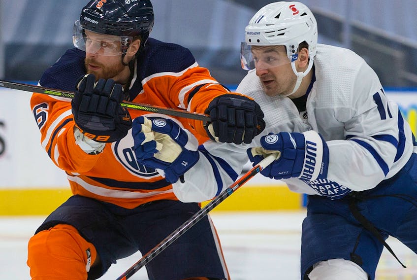 The Edmonton Oilers' Adam Larsson (6) battles the Toronto Maple Leafs' Zach Hyman (11) at Rogers Place in Edmonton on Saturday Feb. 27, 2021.