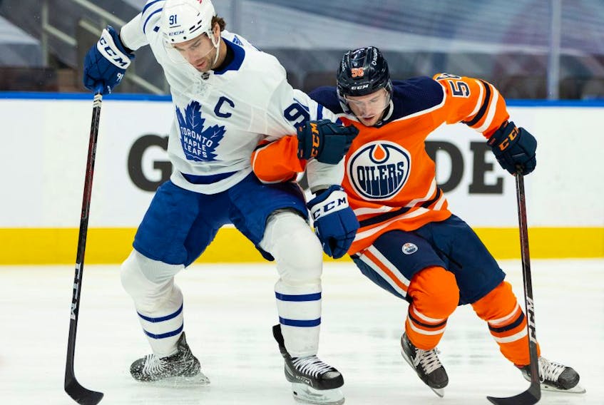 Edmonton Oilers forward Kailer Yamamoto (56) battles Toronto Maple Leafs forward John Tavares (91) during first period NHL action at Rogers Place in Edmonton, on Monday, March 1, 2021. 