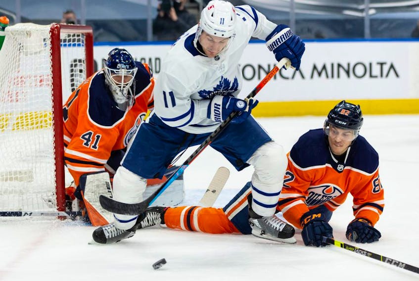 Edmonton Oilers goaltender Mike Smith (41) and Caleb Jones (82) battle Toronto Maple Leafs’ Zach Hyman (11) during second period NHL action at Rogers Place in Edmonton, on Monday, March 1, 2021. 