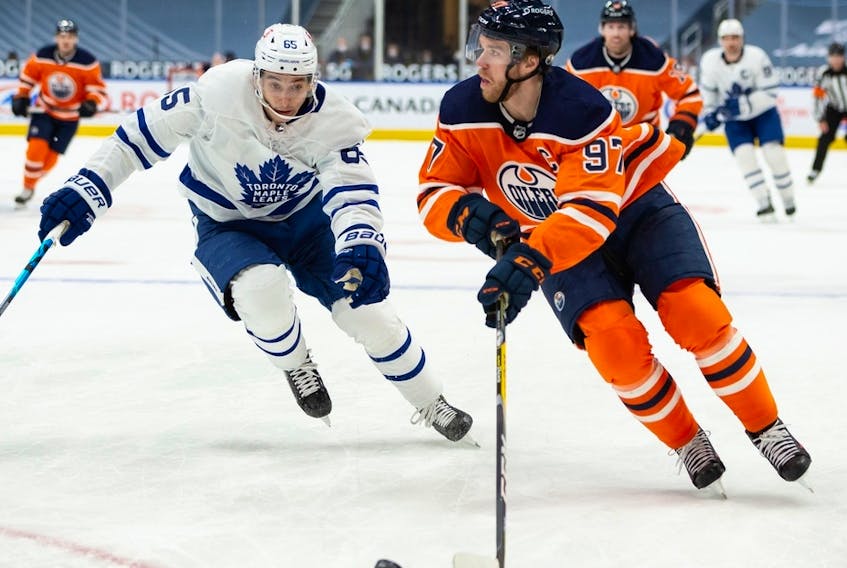 Edmonton Oilers captain Connor McDavid (97) is chased by the Toronto Maple Leafs’ Ilya Mikheyev (65) at Rogers Place in Edmonton on Wednesday, March 3, 2021.
