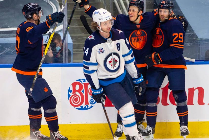 Edmonton Oilers’ Leon Draisaitl (29) celebrates a goal on Winnipeg Jets’ goaltender Connor Hellebuyck (37) with teammates during third period NHL action at Rogers Place in Edmonton, on Saturday, March 20, 2021. 