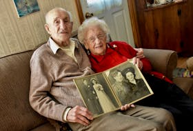 Charlie and Annie Muise sit in their Tusket, Yarmouth County, home holding a wedding photo of themselves, taken nearly 80 years ago, and another photo from their younger years. This couple, who still live together at home, has reached an amazing milestone. Charlie turned 100 on Aug. 3, 2021, and Annie's 100th birthday is Jan. 13, 2022. TINA COMEAU • TRICOUNTY VANGUARD