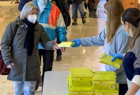People pick up rapid antigen test kits at the Place d'Orléans Shopping Centre, on Monday, Jan. 3, 2022.