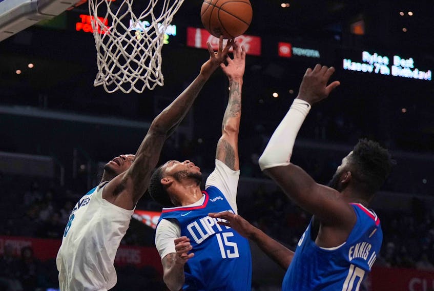 Minnesota Timberwolves forward Jarred Vanderbilt (8) and L.A. Clippers guard Xavier Moon (15) and forward James Ennis (10) reach for the ball at Crypto.com Arena in Los Angeles on Jan. 3, 2022.