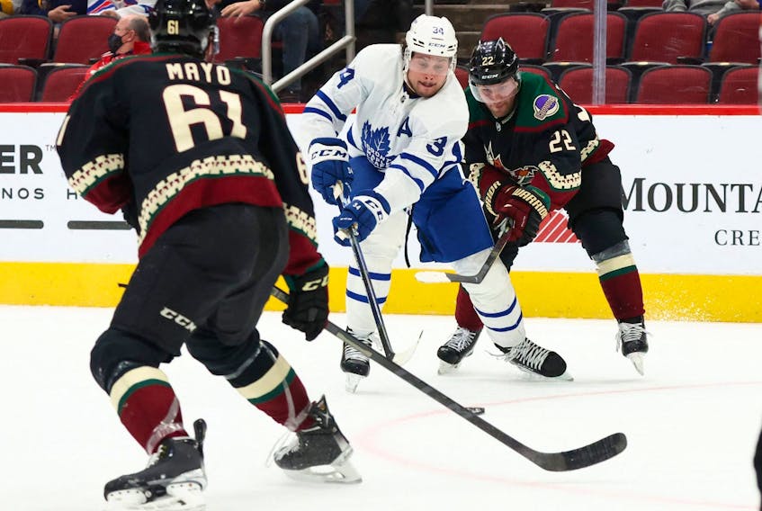 Toronto Maple Leafs centre Auston Matthews (34) passes the puck between Arizona Coyotes left wing Johan Larsson (22) and  Dysin Mayo (61) during the first period at Gila River Arena on Wednesday. 