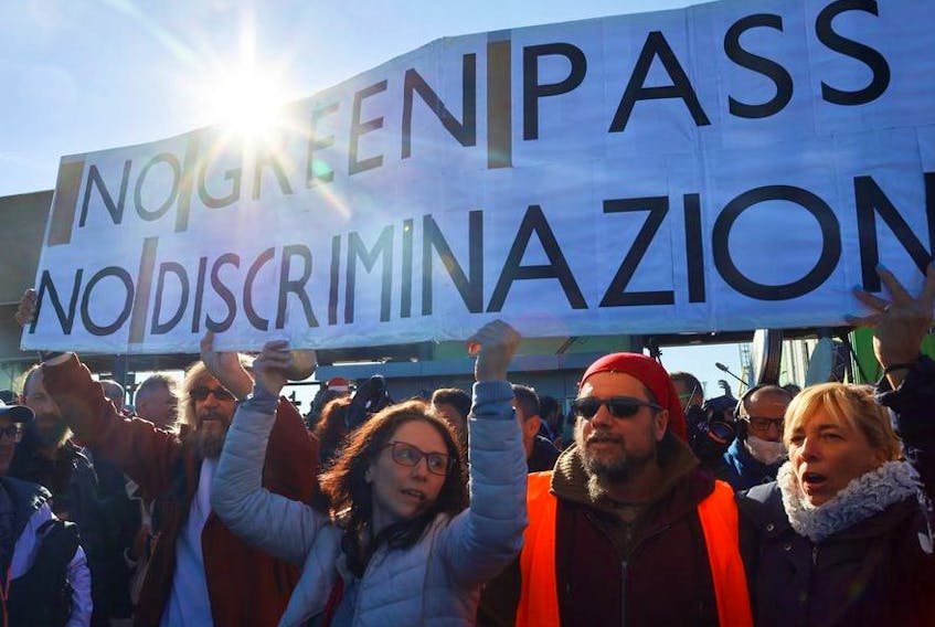 People carry banners as they participate in a protest against the implementation of the COVID-19 health pass, the Green Pass, in the workplace as they gather outside the entrance of the major port of Trieste, Italy, October 15, 2021.  