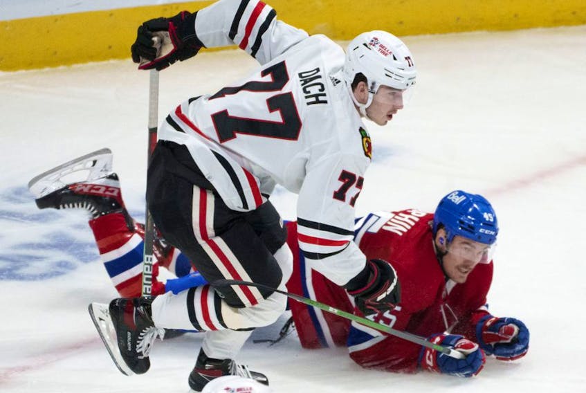 Montreal Canadiens' Laurent Dauphin is tripped by Chicago Blackhawks' Kirby Dach during first period NHL hockey action in Montreal Dec. 9, 2021.