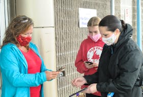 Event staff check the QR Codes and photo IDs of patrons entering the 29th annual Christmas at the Glacier show last month in Mount Pearl.
