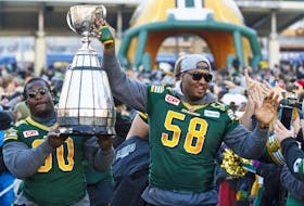 Edmonton Elks Almondo Sewell (90) and Tony Washington (58) carry the Grey Cup into a Grey Cup rally at Churchill Square in Edmonton on Dec. 1, 2015. 