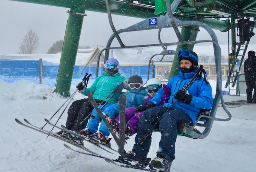 The Williams family settles in on the chairlift for their second run of the day on Sunday at Ski Ben Eoin. From left, Sarah, Henry, Fiona and Blair Williams raise their ski tips as the chair begins to climb the mountain. DAVID JALA/CAPE BRETON POST