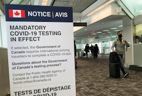 Travelers walk past a mandatory COVID-19 testing sign at Pearson International Airport in Toronto on Dec. 18, 2021.