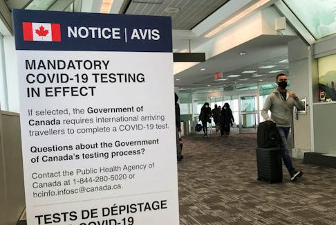Travelers walk past a mandatory COVID-19 testing sign at Pearson International Airport in Toronto on Dec. 18, 2021.