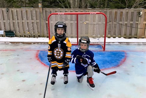 Brothers William and Blake Butcher enjoying their backyard rink which even includes painted lines and goalie creases.