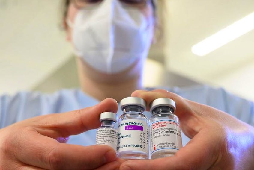 A woman wearing a face mask shows three vials with different vaccines against COVID-19 by (from left to right) Pfizer-BioNTech, AstraZeneca and Moderna in the pharmacy of the vaccination centre at the Robert Bosch hospital in Stuttgart, Germany, on Feb. 12, 2021.