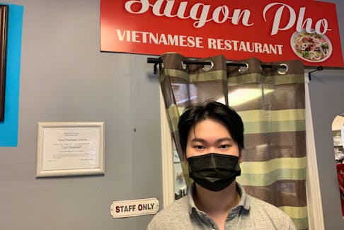 Saigon Pho owner Kevin Huynh stands inside his restaurant where he says that some days, he sees one or two customers dine-in. 
