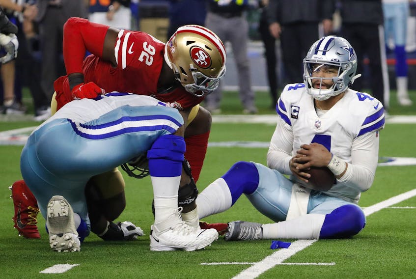 Dallas Cowboys quarterback Dak Prescott, right, holds the ball after recovering his own fumble on a sack by San Francisco 49ers defensive end Charles Omenihu (92) during the second half of an NFL wild-card playoff football game in Arlington, Texas, Sunday, Jan. 16, 2022. 