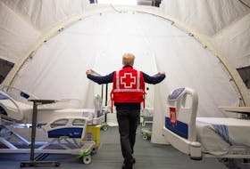  A Red Cross volunteer walks between beds in a mobile hospital set up to help care for COVID-19 patients in Montreal, April 26, 2020. Hospitals in Quebec and Ontario are currently being pushed to the breaking point by the effects of the Omicron variant.