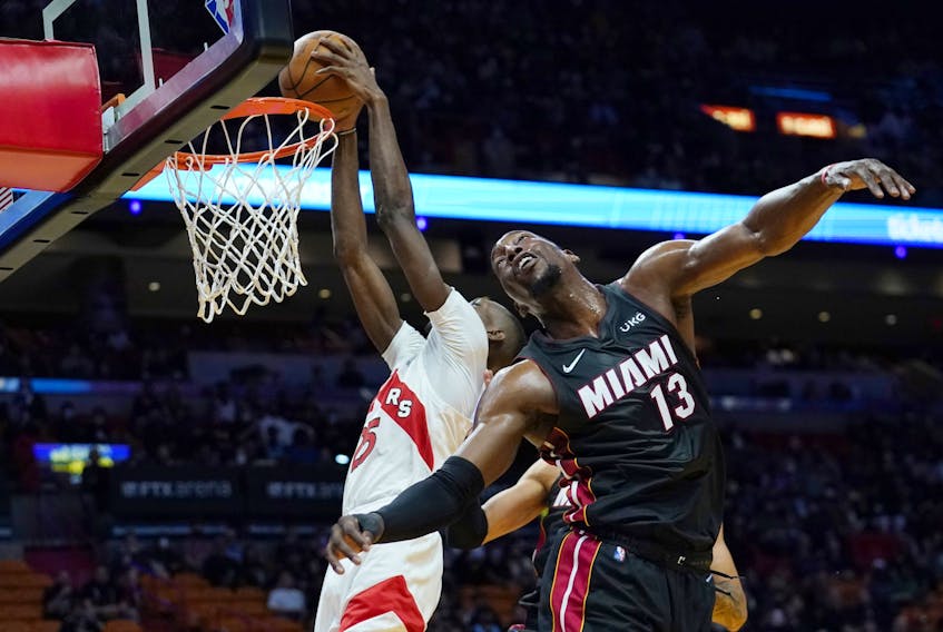 Raptors' forward Chris Boucher (left) dunks over Miami Heat's Bam Adebayo during the first half on Monday, Jan. 17, 2022, in Miami. 