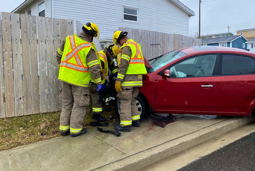 Firefighters check the front end of a car that crashed through a fence on Hamlyn Road following a collision with a truck near the Canada Drive intersection.