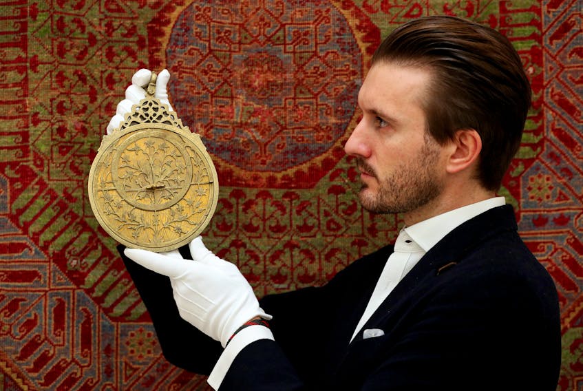 A Sotheby's employee displays a royal Mughal planispheric astrolabe during ahead of the auction house's Islamic World, Legendary Timepieces and Middle Eastern Art sales in October 2020.  PA Images via Reuters