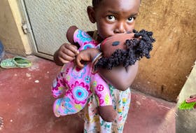 A young girl in Uganda embraces her baby doll with a kiss. This doll was one of 21 knitted by Linda Berberick and delivered by Eddie Joyce during his recent visit to a Ugandan orphanage. CONTRIBUTED
