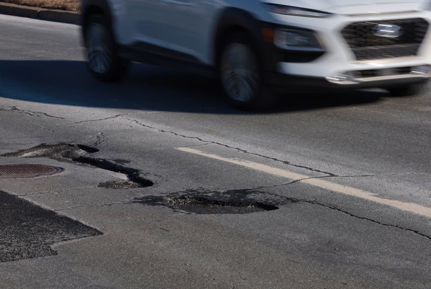 Drivers try to avoid potholes along Main Street in Dartmouth Friday. A report coming to Halifax Regional Council recommends a new standard for the state of roads — that 67 of them should be classified as “good”.