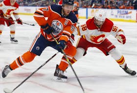 Edmonton Oilers forward Connor McDavid (97) tries to carry the puck around Calgary Flames defencemen Oliver Kylington at Rogers Place in Edmonton on Saturday, Jan. 22, 2022.