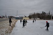 Edwin Leporte, left, throws pucks out to the neighbourhood kids practicing their hockey skills on the outdoor rink in Membertou on Saturday. Leporte, 43, remembers skating at that same spot as a kid himself. ARDELLE REYNOLDS/CAPE BRETON POST