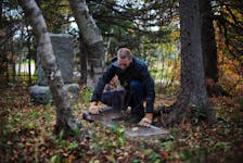Photographer and writer Steve Skafte visits abandoned cemeteries across Nova Scotia in an effort to preserve them. Here he is shown examining a grave at Sydney River’s Howie Family Burial Ground off Riverside Drive. CONTRIBUTED/STEVE SKAFTE