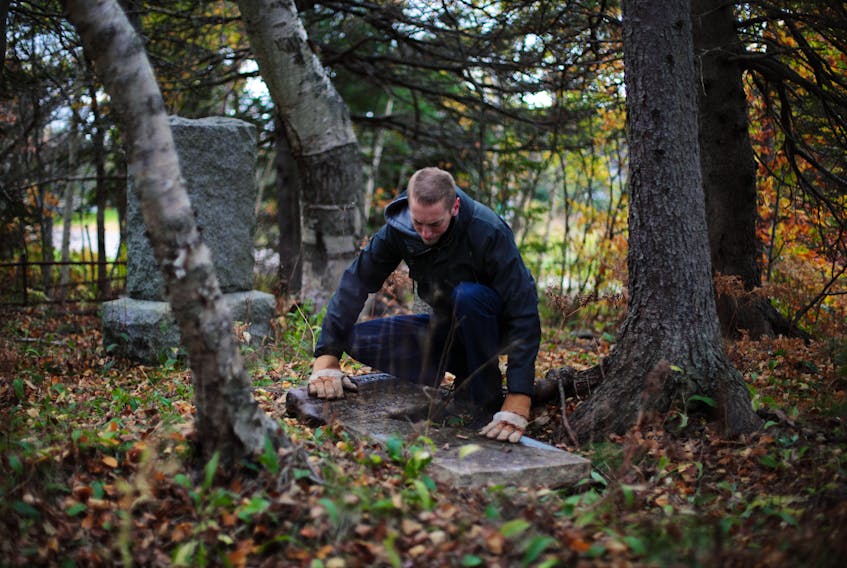 Photographer and writer Steve Skafte visits abandoned cemeteries across Nova Scotia in an effort to preserve them. Here he is shown examining a grave at Sydney River’s Howie Family Burial Ground off Riverside Drive. CONTRIBUTED/STEVE SKAFTE