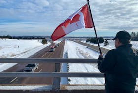 Robert Henri of Wentworth holds a Canadian flag on the Fort Lawrence Road overpass Sunday as protesters vehicles pass below on the Trans-Canada Highway near the Nova Scotia-New Brunswick border. Darrell Cole – SaltWire Network