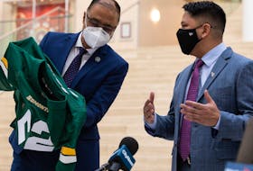 Edmonton Mayor Amarjeet Sohi (left) receives an Edmonton Elks jersey from new club president and CEO Victor Cui at City Hall on Tuesday, Jan. 25, 2022. 