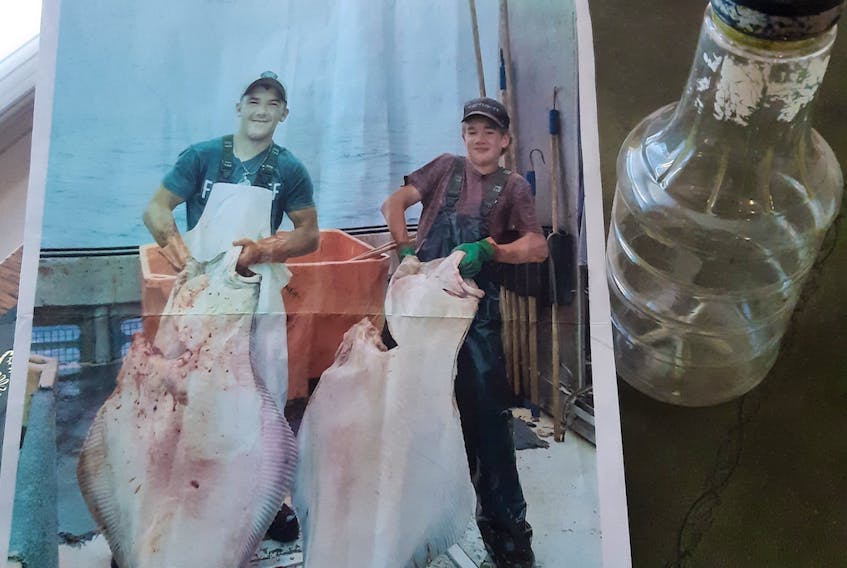 Yarmouth County, Nova Scotia, teenagers Orren Hatfield and Daniel Kenney each hold a halibut caught during a fishing trip off Newfoundland last summer. A note was written on the back of this photograph, put in a bottle and tossed overboard on July 16, 2021. On Jan. 7, 2022, the note and bottle were found on a shoreline in England. CONTRIBUTED