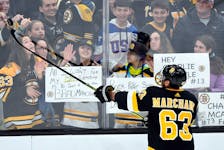 Boston Bruins left-winger Brad Marchand (63) tosses a puck to fans before a game against the Arizona Coyotes at the TD Garden.