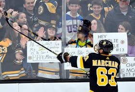 Boston Bruins left-winger Brad Marchand (63) tosses a puck to fans before a game against the Arizona Coyotes at the TD Garden.