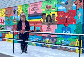 Artist Barbara Palmer stands in front of the large mural she painted on the Boys and Girls Club of Cape Breton in Whitney Pier. Consisting of 40 puzzle pieces, the work represents how the club connects youth and the community. Chris Connors/Cape Breton Post