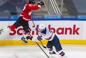 Canada’s Dylan Cozens (left) leaps as he is checked by USA’s Jake Sanderson at the world junior hockey championship last year. 