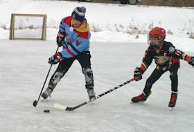 Owen Smith, left, tries to protect the puck from Lane Hein Jan. 23 at the outdoor rink in Sheffield Mills.