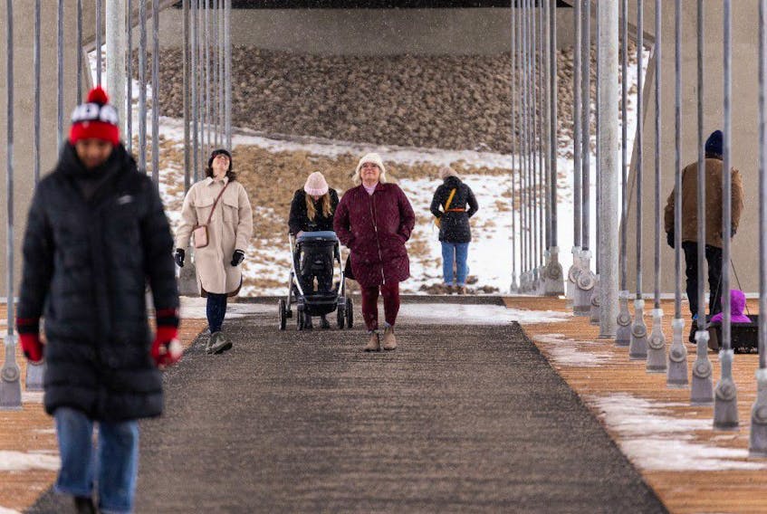 People cross the Tawatinâ Bridge on a snowy morning in Edmonton, on Wednesday, Jan. 26, 2022. The bridge connects the Cloverdale neighbourhood with downtown and was constructed as part of the Valley Line LRT. 