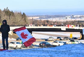 Anthony Archibald with a large Canadian flag offering support to the truckers’ convoy. In the background is the exit 13 overpass where many other supporters gathered.