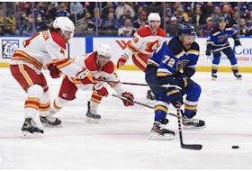 Calgary Flames defenceman Rasmus Andersson (4) and winger Johnny Gaudreau (13) defend against St. Louis Blues defenceman Justin Faulk at Enterprise Center in St. Louis on Thursday, Jan. 27, 2022.