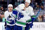  Tanner Pearson #70 of the Vancouver Canucks celebrates his empty-net goal with Tyler Myers #57 and Bo Horvat #53 during the third period against the Seattle Kraken at Climate Pledge Arena on January 01, 2022 in Seattle, Washington.