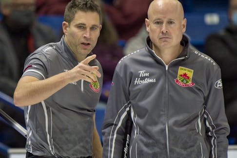 Skip Kevin Koe of Calgary, right, and second John Morris review their options 
against team Brendan Bottcher during the Tim Hortons Curling Trials in Saskatoon on Nov. 24, 2021.