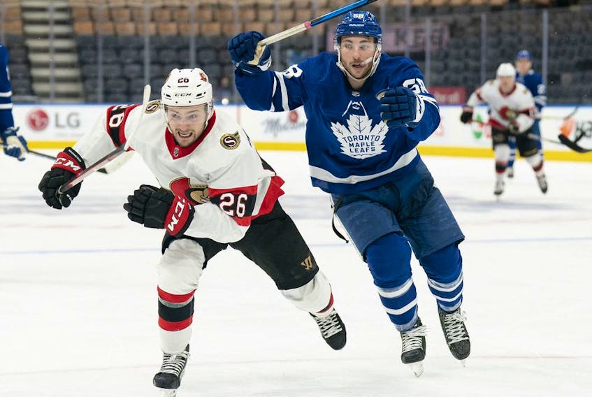  Ottawa Senators defenceman Erik Brannstrom (26) and Toronto Maple Leafs left wing Michael Bunting (58) chase down the puck during the third period at Scotiabank Arena, Jan. 1, 2022.