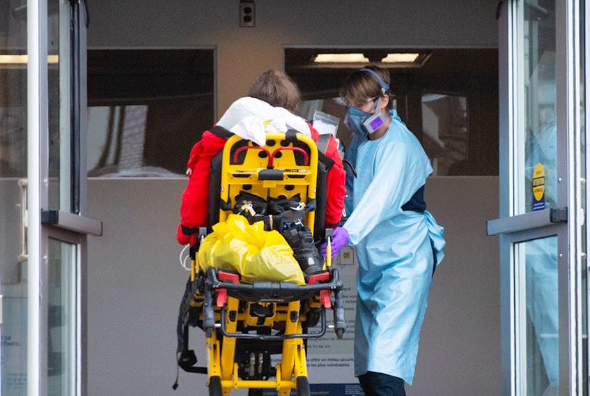  A patient is taken into a hospital by a paramedic in Montreal, December 29, 2021. Quebec is experiencing its third-highest number of COVID-19 hospitalizations since the pandemic began. But this is despite a rate of new cases that is at least four times higher than anything yet seen.