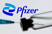  A syringe and vial are seen in front of a displayed Pfizer logo in this illustration PHOTO taken June 24, 2021.